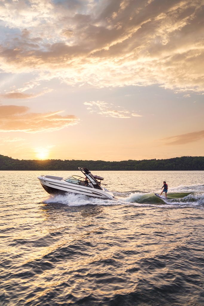 Kid wakesurfing behind an SDX 230 Surf at sunset