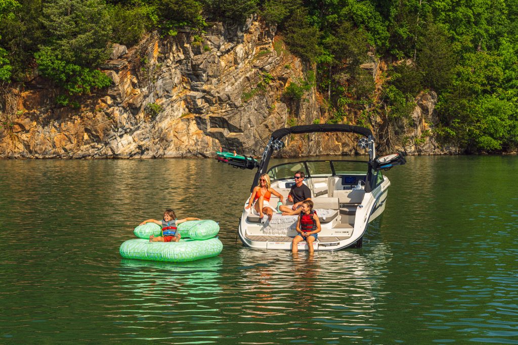 Kid floating on an inflatable next to an SDX 230 Surf while his family watches
