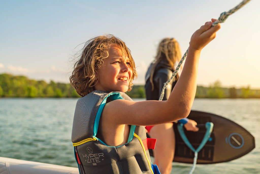 Mother and son with wakesurf board and tow line aboard an SDX 230 Surf