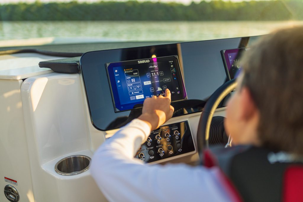 Kid using a touchscreen display at the helm of an SDX 230 Surf