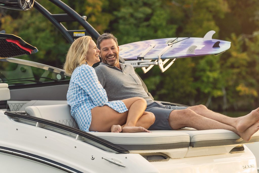 Couple lounging on the sunpad of an SLX 260 Surf