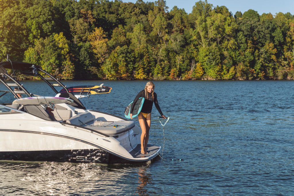 Woman with wakesurf board on an SLX 260 Surf