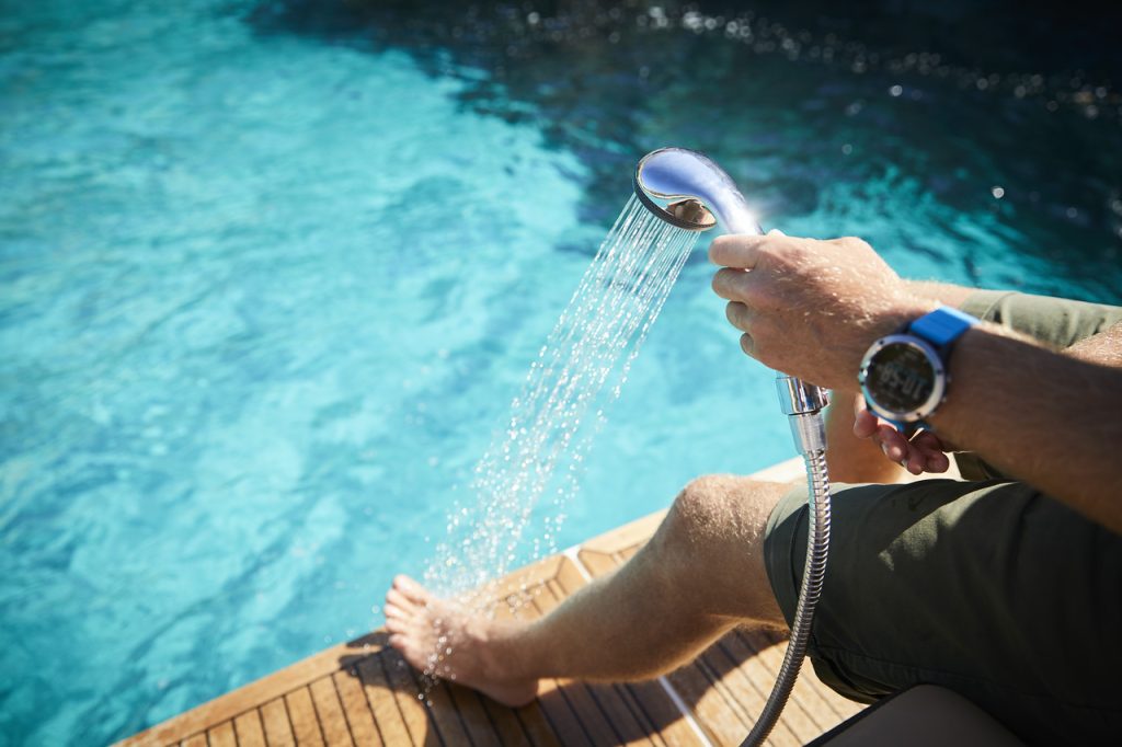 Man rinsing his feet with the pull-out sprayer on a Sundancer 320