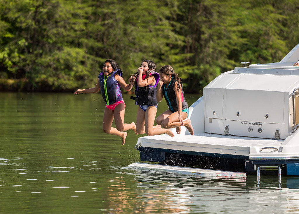 Kids jumping in the water from a Sundancer 320