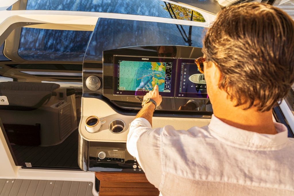 Man using a touchscreen display at the helm of a Sundancer 370 Outboard