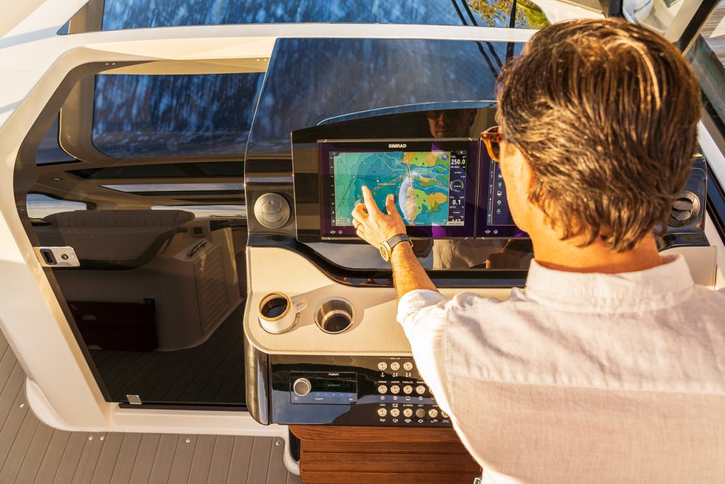 Man using a touchscreen display at the helm of a Sundancer 370 Outboard