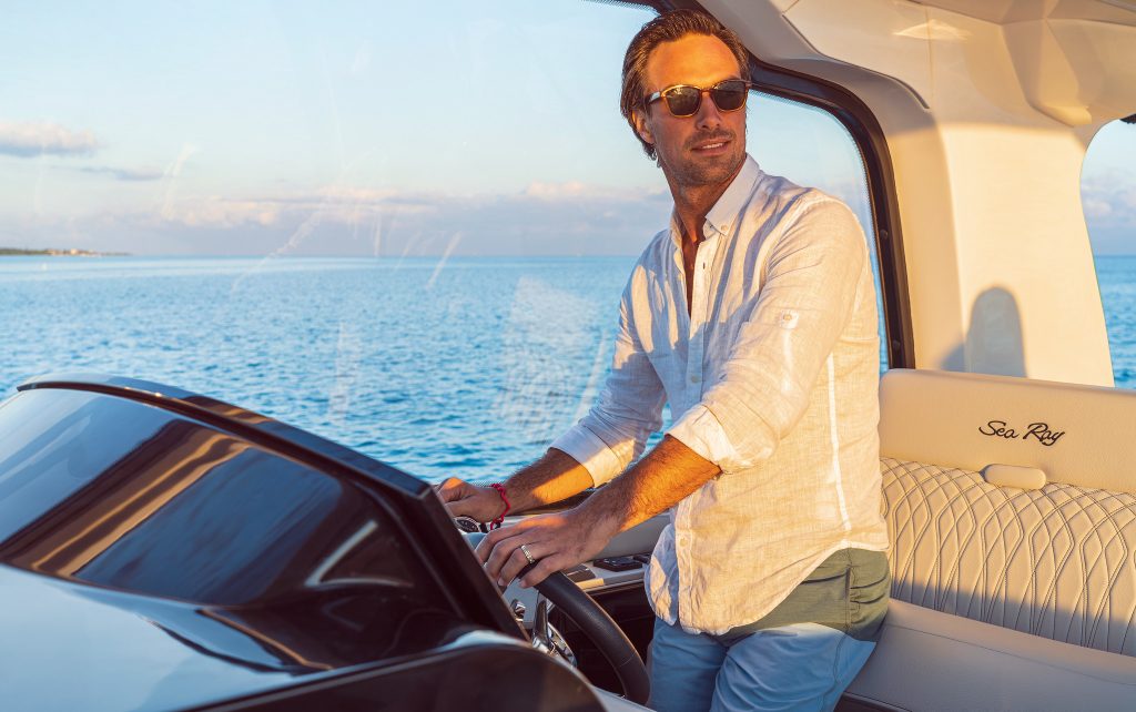 Man with sunglasses at the helm of a Sundancer 370 Outboard